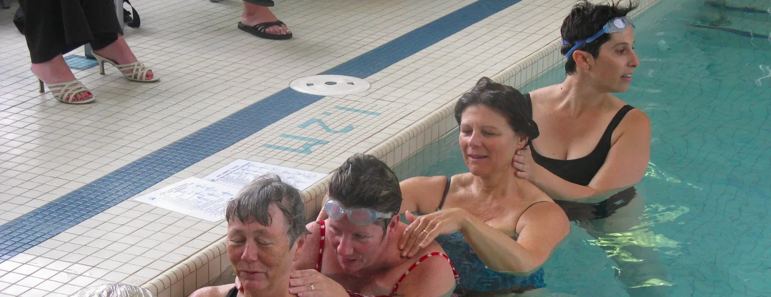 A therapist guiding a patient through aqua lymphatic therapy in a pool